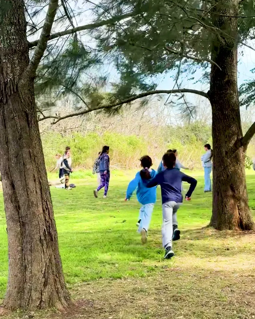 Chicos corriendo entre los árboles del parque